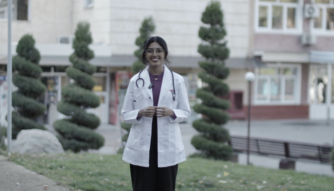 MBBS student in white coat with stethoscope outside her university